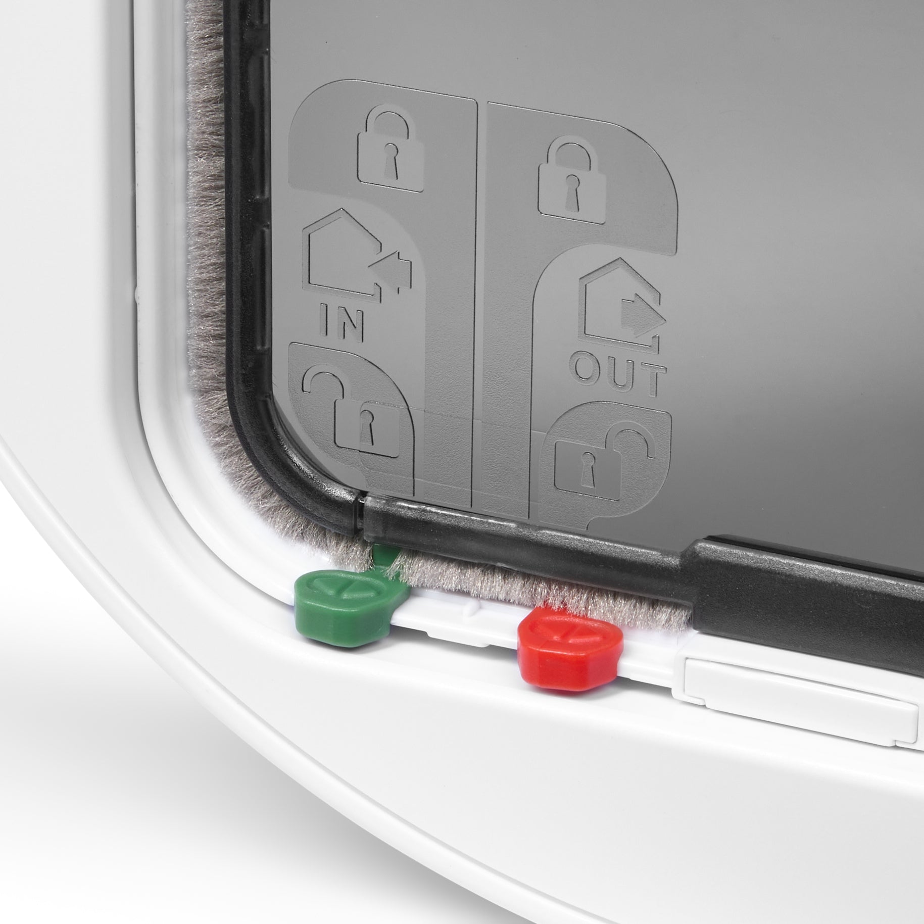 A close-up view of the red and green manual locks and the weather-proof and draught-proof brush seal on the white pet door for cats and small dogs on a white background