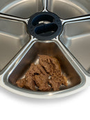 A portion of wet pet food sits in the stainless steel dish nearest to the camera