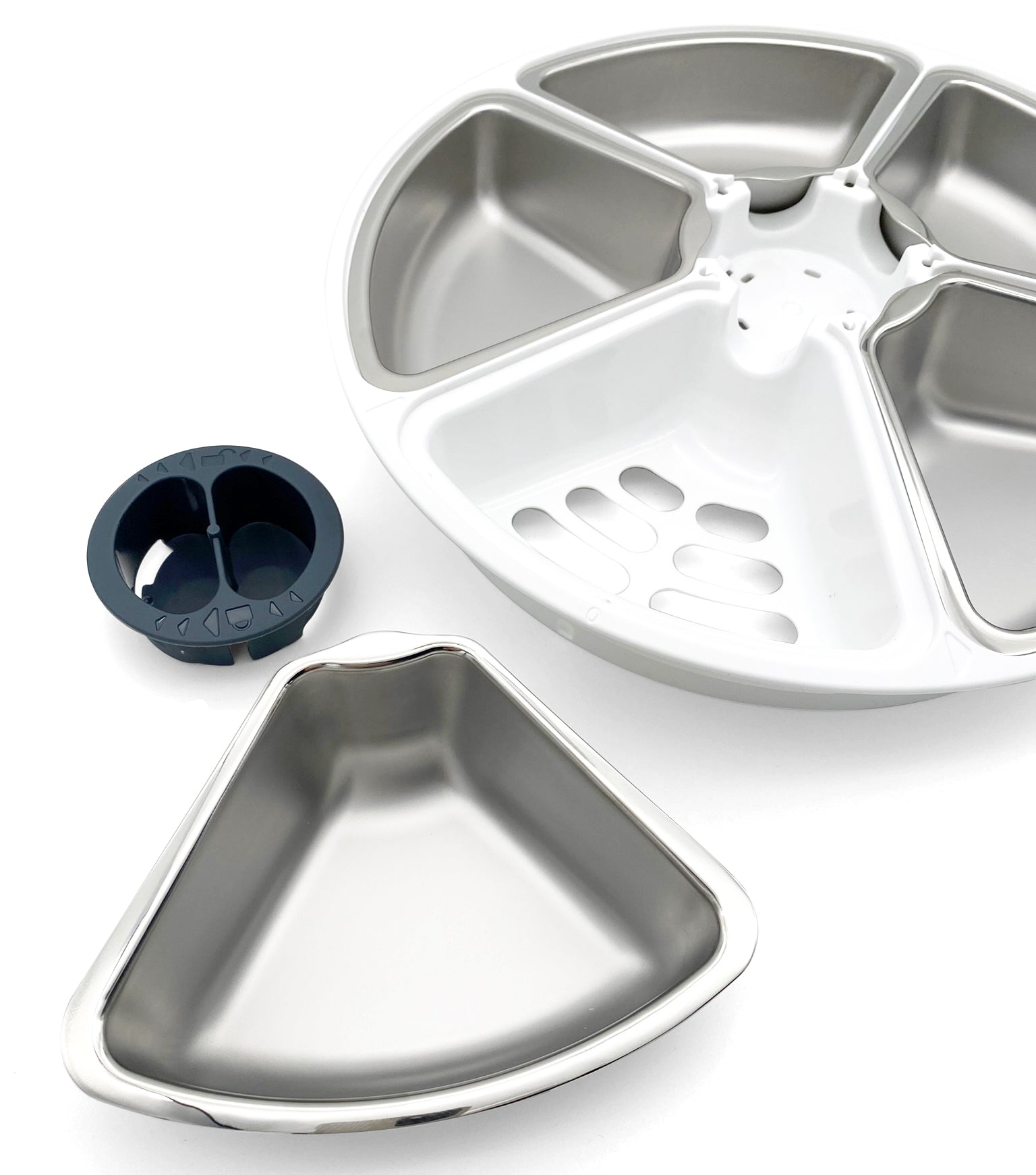 A stainless steel bowl insert is next to a white carousel dish containing the other four stainless steel dish inserts on a white background