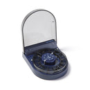 A dark blue fish feeder with a clear lid and dark food portion carousel on a white background