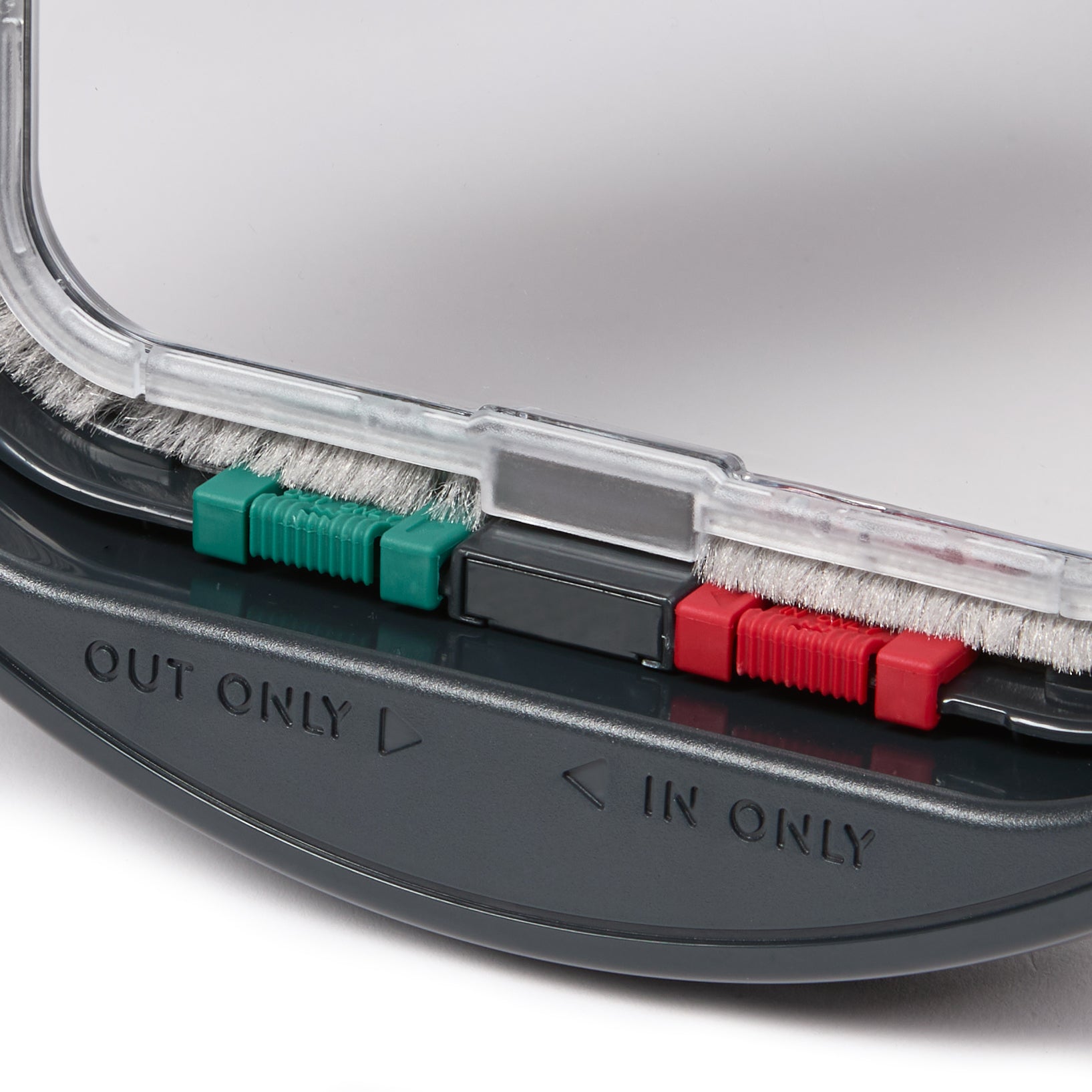Close-up of the bottom panel of the grey cat flap displaying the red and green manual locks  and 'IN ONLY' and 'OUT ONLY' labels with directional arrows beside them. 