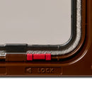 Close-up of a red lock and draft proof brushing on the brown cat flap on a white background.