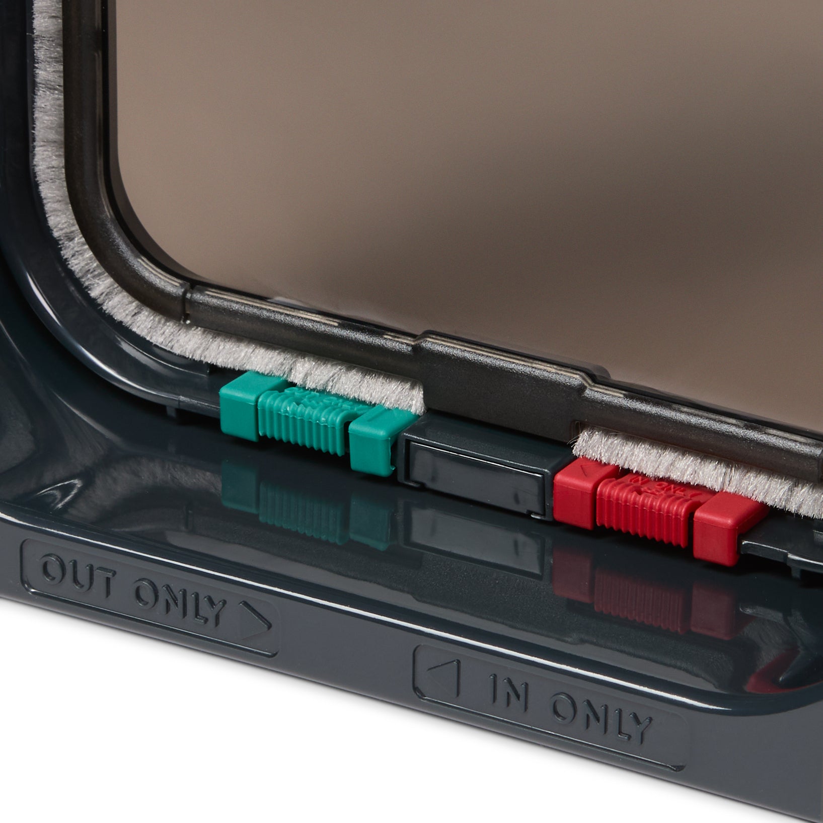 A close-up view of the red and green manual locks on the grey cat flap with 'in only and 'out only' labels underneath with directional arrows beside them, on a white background 