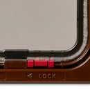 Close-up of the red lock mechanism on the brown cat flap that is locked or unlocked manually on a white background 