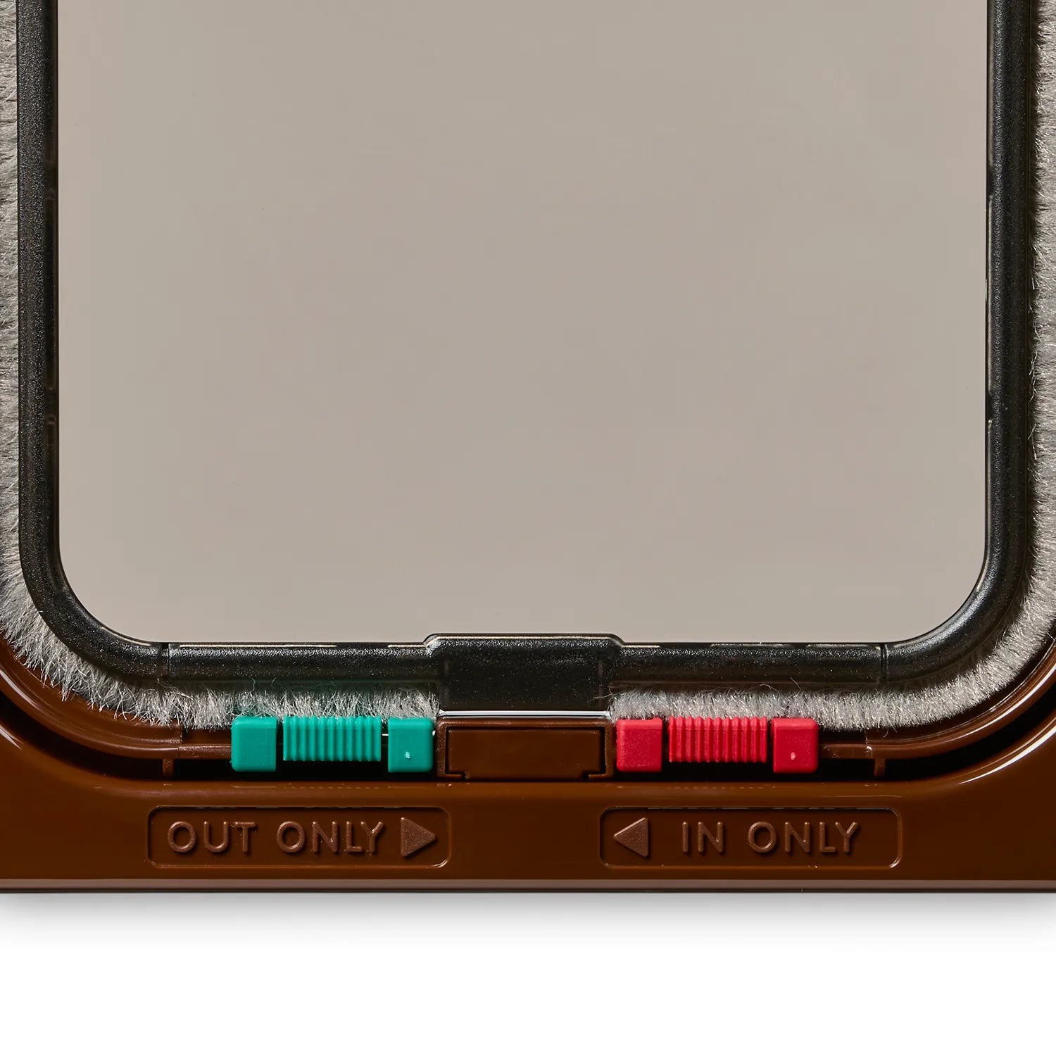 Close up view of the bottom of the brwn cat flap which displays the red and green locks, as well as the 'Out Only' and 'In Only' labels underneath, on a white background 