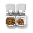 Automatic pet feeder suitable for cats and small dogs with two compartments filled with kibble in one and wet food in the other on a white background
