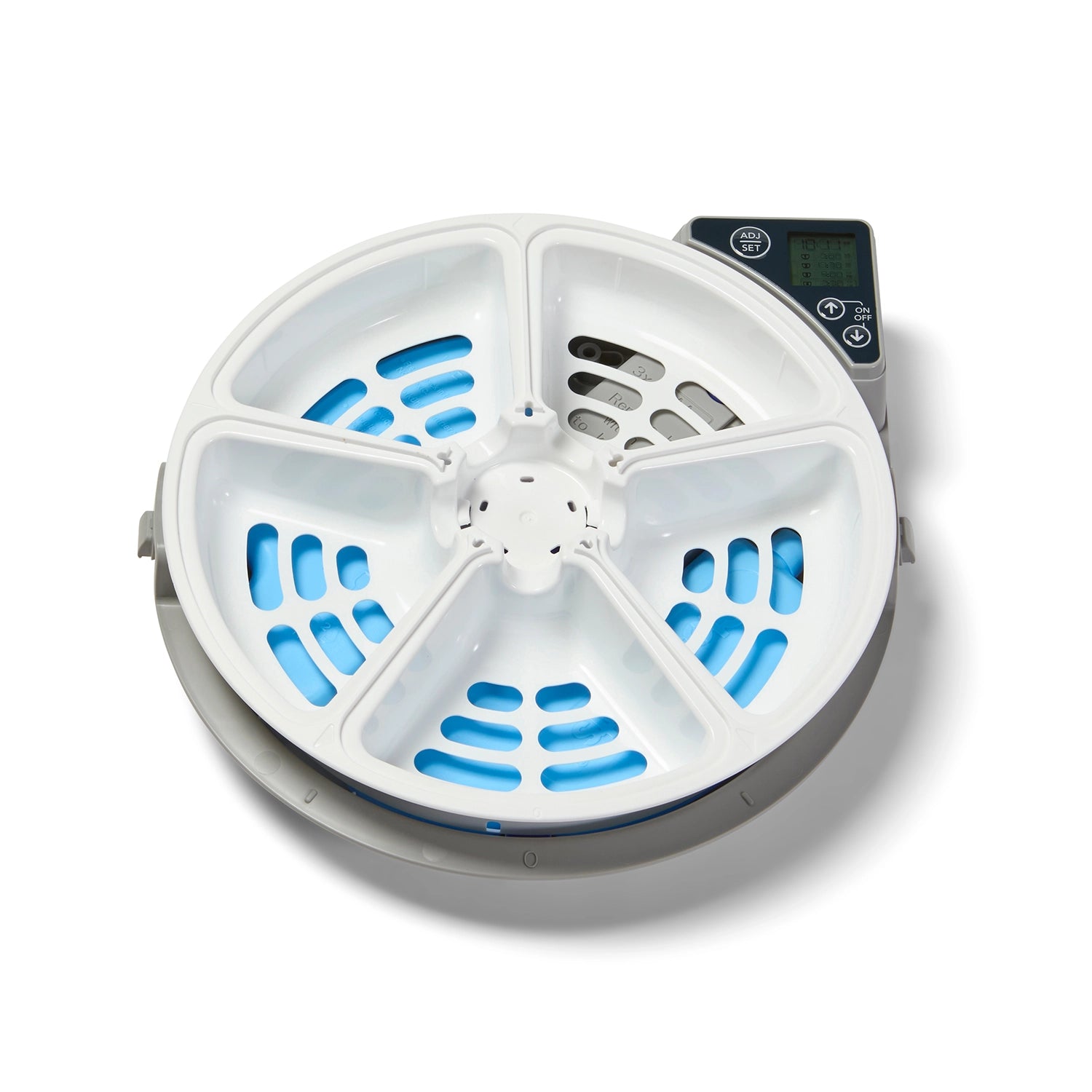 Top-down view of the inside of a circular automatic pet feeder. The feeder contains a white five-compartment rotating tray with ventilation slots revealing blue ice packs beneath, designed to keep wet food cool. At the top right, there is a digital control panel with a display screen and buttons for programming feeding times. The compartments are evenly spaced, allowing for multiple scheduled meals
