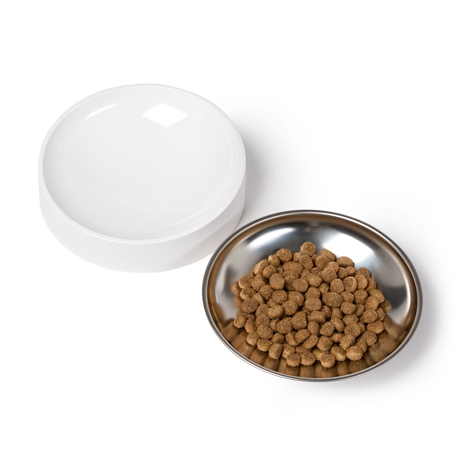 White plastic feeder base of the Cat Mate 4L WIFI feeder beside a round stainless steel bowl filled with brown kibble, shown on a plain white background.