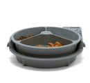 A grey automatic pet feeder with a circular tray divided into three compartments, containing different types of wet and dry pet food. 