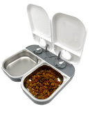 A side on view of the two meal automatic pet feeder with open lids, one stainless steel bowl is empty and the other bowl contains dry pet food  